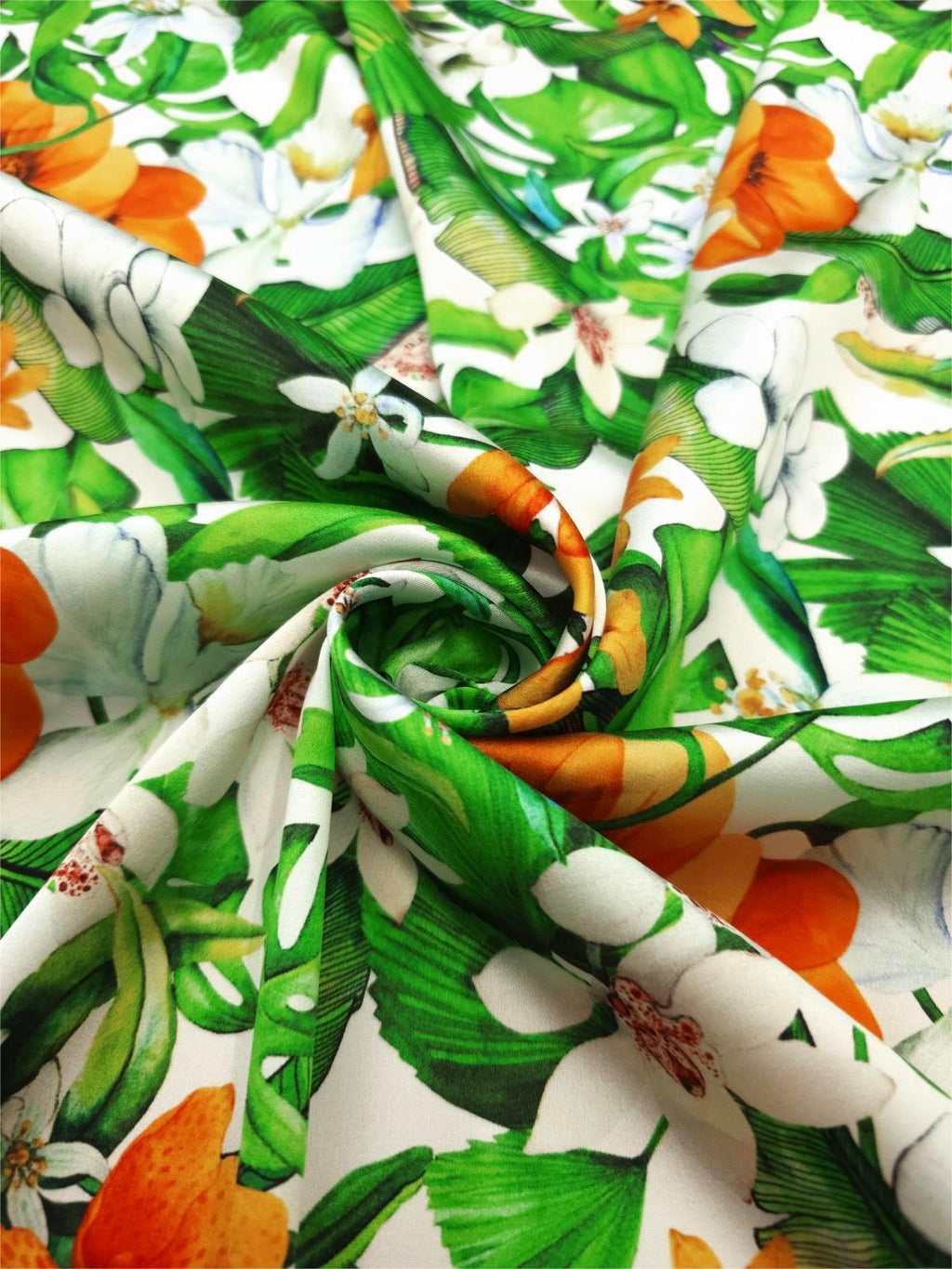 Italian printed silk satin arranged in soft folds, showing green leaves, white flowers and orange blooms.