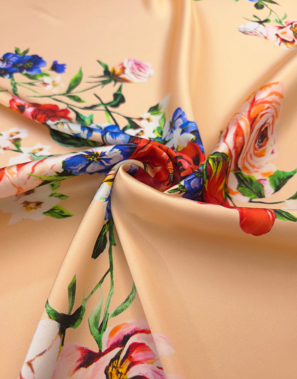Luxury Italian silk satin fabric with vibrant red and blue flowers on a soft peach background