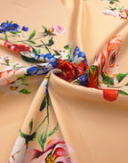 Luxury Italian silk satin fabric with vibrant red and blue flowers on a soft peach background
