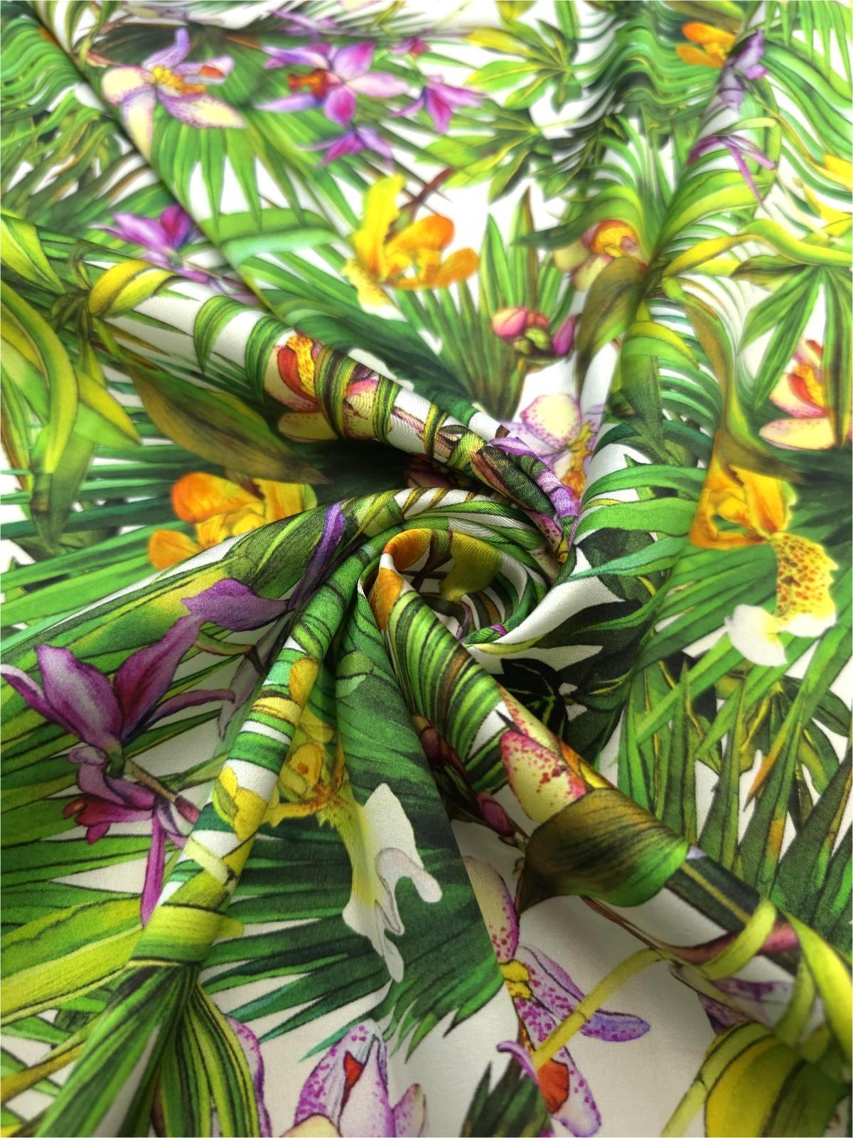 Italian Mulberry silk satin with colorful tropical orchids and layered green leaves on a white background